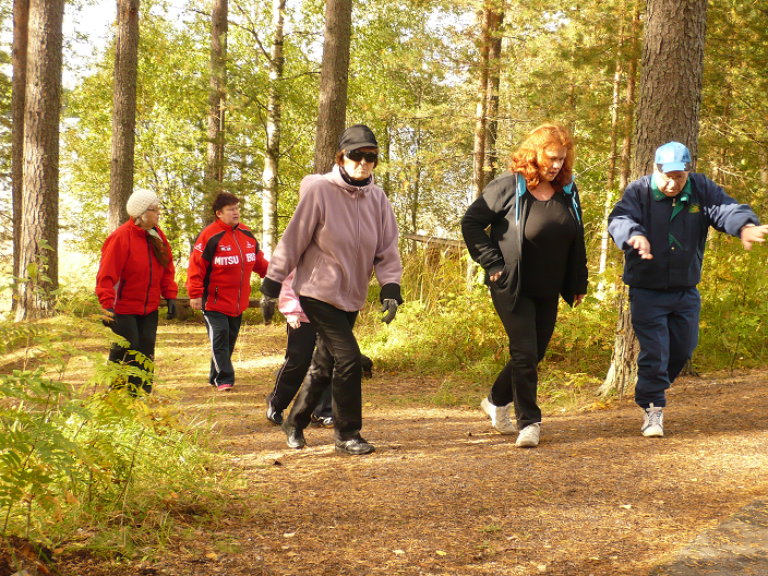 Kuva perhekurssista Peurungasta. Kuvassa kuusi henkilöä kävelee metsäpolulla.